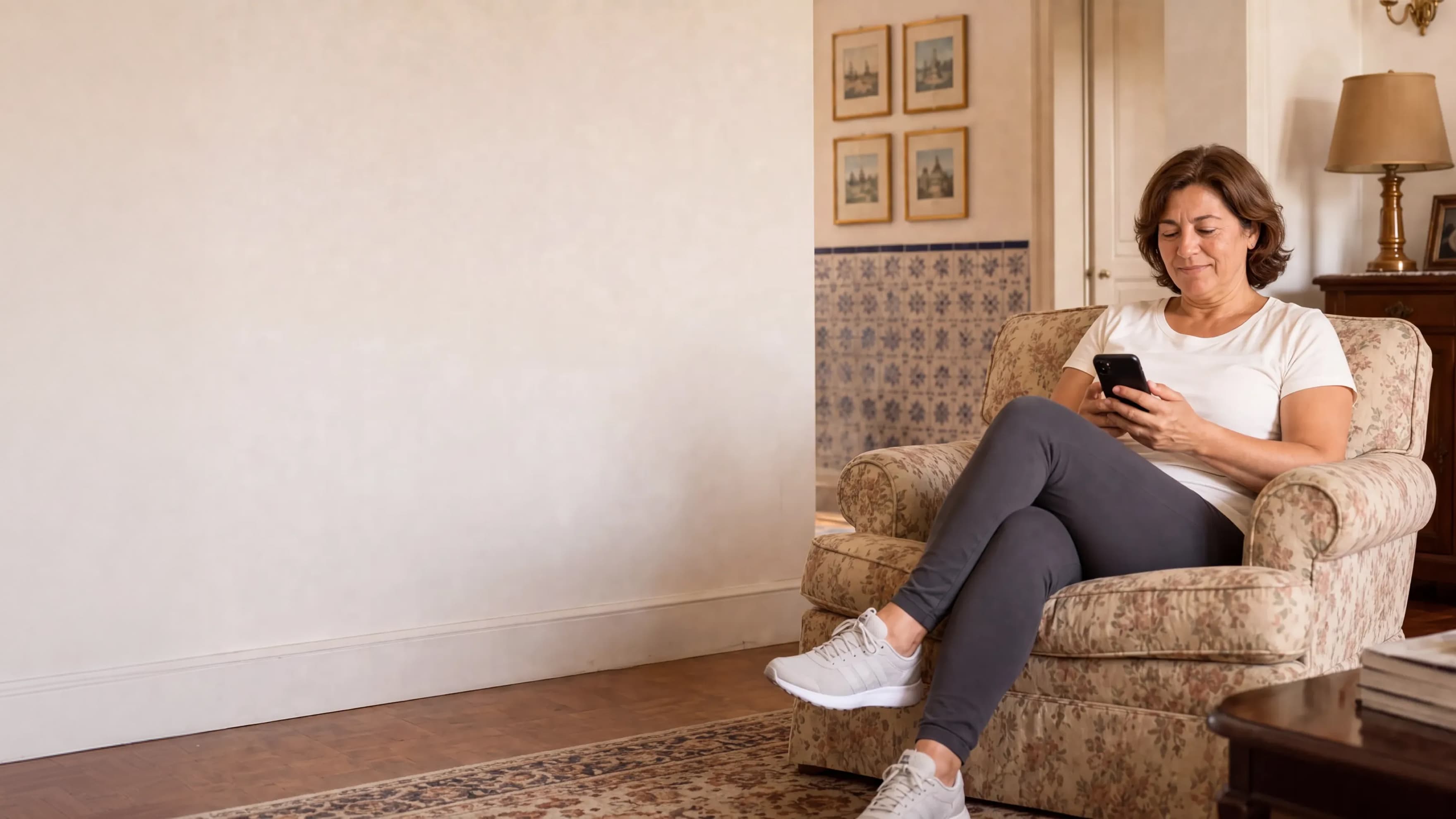A woman sitting in an armchair while looking at her smartphone.