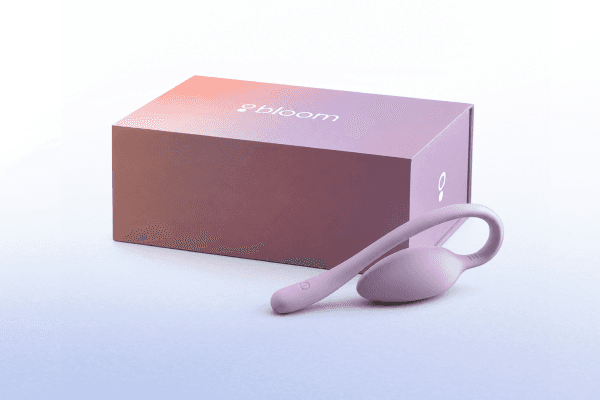A purple wearable tech device with a flexible loop lies next to a purple box labeled "Bloom" on a light gradient background.